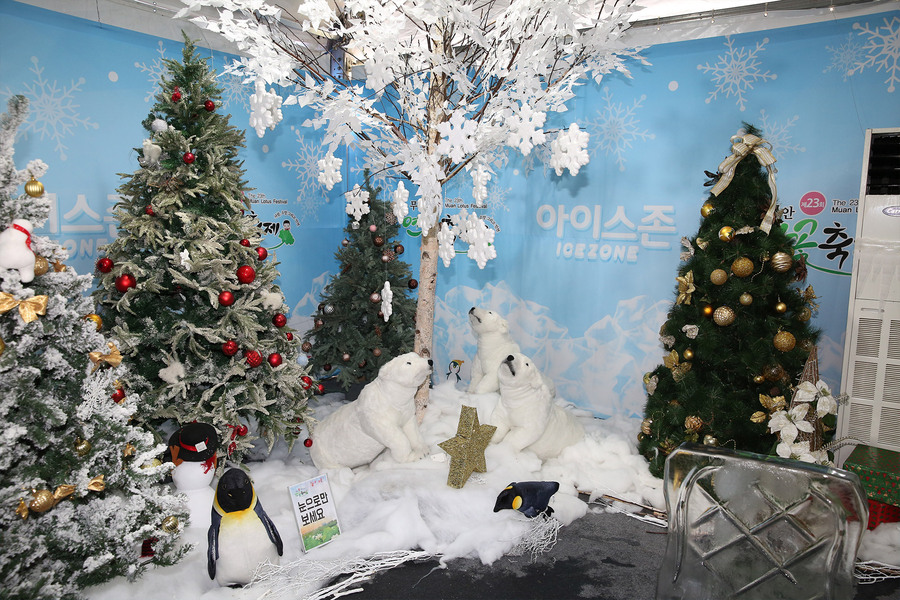 하얀 눈이 쌓인 크리스마스 트리와 백곰 인형 3마리와 펭귄 인형이 장식되어 있는 모습