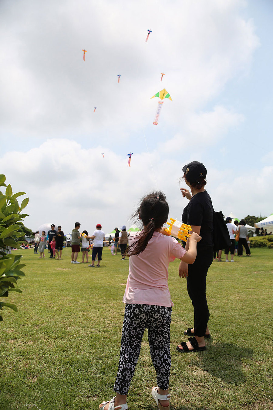 어린여자아이와 엄마가 연을 날리며 하늘을 바라보고 있는 모습